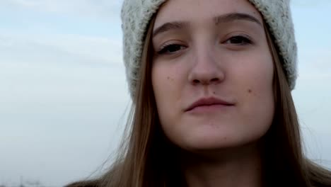 Portrait-of-a-teenage-girl-in-a-knitted-cap,-which-showing-and-eating-Israeli-peanut-snacks-Bamba,-outdoor,-stock-footage.