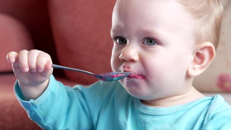 Un-atractivo-chico-de-2-años-come-una-ensalada-de-remolacha-roja.-La-cara-está-manchada-con-gachas-de-avena.-Se-sienta-en-la-mesa