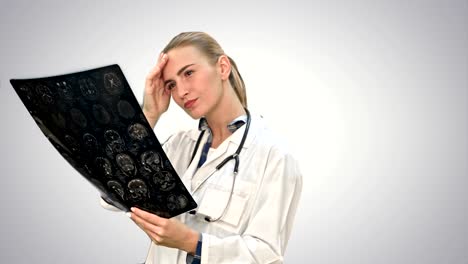 Female-doctor-looking-seriously-at-xray-results-of-human-brain-on-white-background