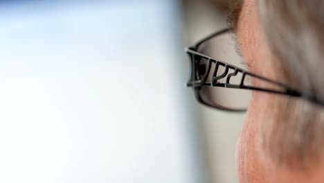 Senior-man-in-glasses-works-for-a-laptop.-He-looks-seriously-at-the-monitor