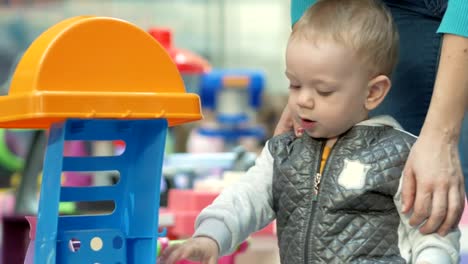 Cute-blond-babe-is-playing-with-toys-in-the-mall.-Children's-area-to-leave-children-when-shopping