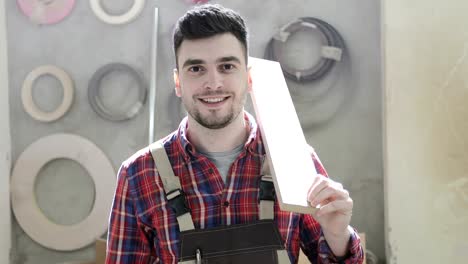 4K-Portrait-of-a-happy-carpenter-holding-a-wooden-board-on-his-shoulder.