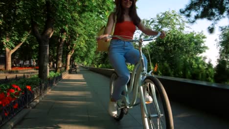 joven-hermosa-mujer-montando-una-bicicleta-en-un-parque