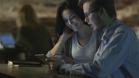 Joven-pareja-están-utilizando-Tablet-PC-para-el-entretenimiento-en-cafetería-por-la-noche.-Estilo-de-vida-casual.