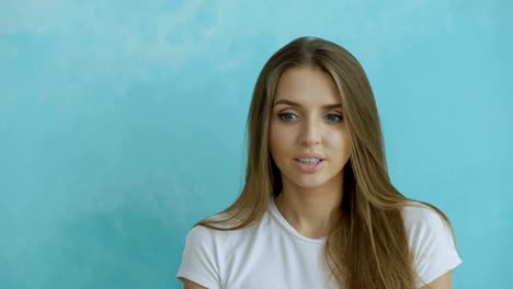 Portrait-of-young-woman-actively-surprising-and-wondering-looking-into-camera-on-blue-background