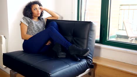 Sad-African-American-girl-sitting-by-the-window-of-urban-loft