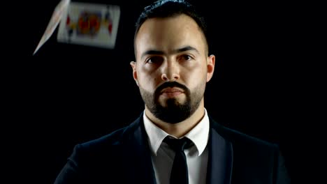 Close-up-Portrait-of-a-Bearded-Illusionist-Looking-at-the-Camera-and-Gaming-Cards-Raining-on-Him-then-He-Pulls-Ten-of-Diamonds-out-of-the-Deck.