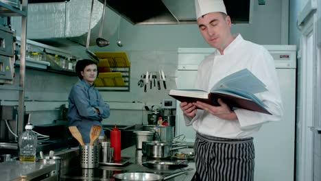 Head-chef-looking-for-a-recipe-in-the-book-for-cook-trainee-to-prepare