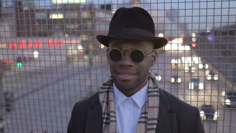 Joven-negro-a-hombres-con-gafas-de-sol,-sombrero-y-bufanda.-Disfrutar-el-día-al-aire-libre-en-la-ciudad