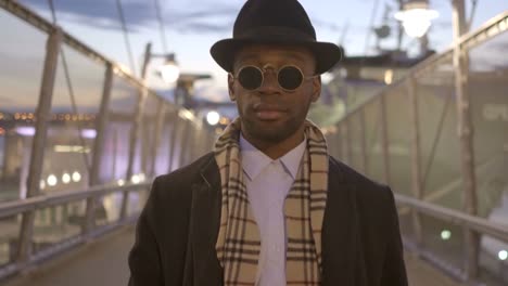 Joven-negro-a-hombres-con-gafas-de-sol,-sombrero-y-bufanda.-Disfrutar-el-día-al-aire-libre-en-la-ciudad