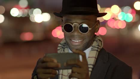 Young-Man-with-African-American-Ethnicity-Wearing-Old-Classic-Look.-Having-Fun-in-the-Big-City-with-Sunglasses,-Hat-and-Scarf.