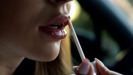 Luxury-woman-paints-her-lips-sitting-in-a-car-salon,-closeup