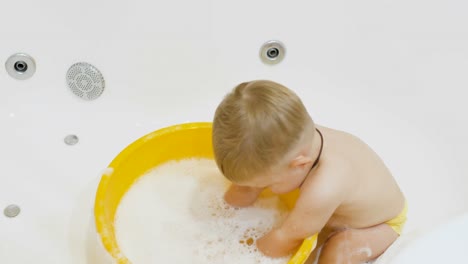 Entzückende-junge-spielen-mit-Wasser-in-der-Badewanne