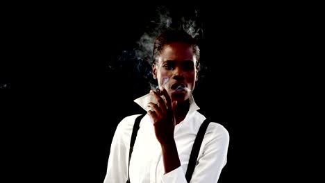 Androgynous-woman-smoking-cigar-against-black-background