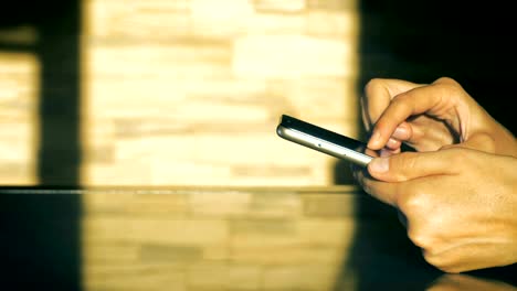 Dolly-close-up-of-a-hand-of-a-young-girl-using-smart-phone-sits-at-a-table-in-kitchen.