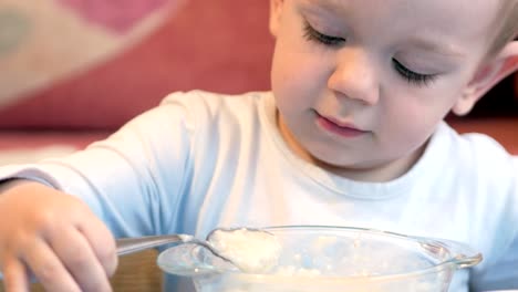 Un-lindo-niño-come-gachas-con-trozos-de-carne-en-la-mesa-de-los-niños.-muebles-para-el-hogar