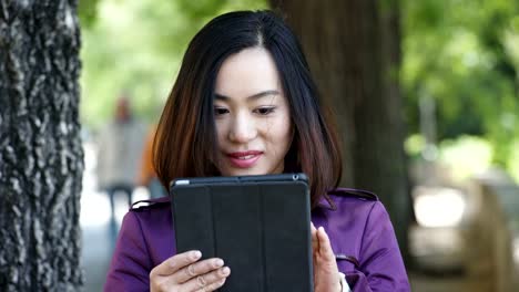 Asiatische-junge-Frau-mit-digitalen-Tablet-und-Lächeln-outdoor