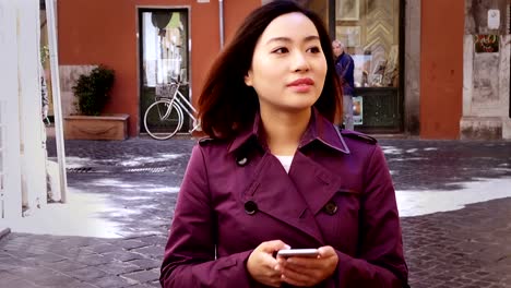 elegant-Chinese-woman-typing-on-the-smartphone-in-the-street,-portrait