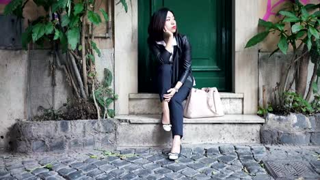 Young-Chinese-woman-bored-waiting-for-a-friend-watching-the-clock,-in-the-street