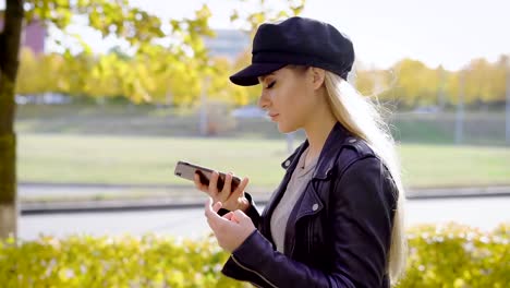 Junge-stilvolle-Modell-mit-Spaziergang-im-Stadtpark-mit-smartphone