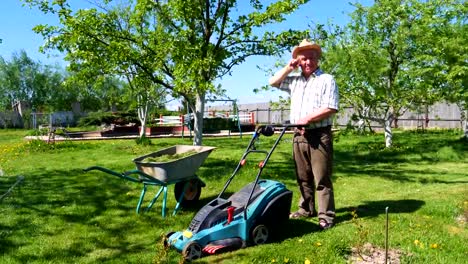 Un-hombre-está-de-pie-con-un-cortacésped-en-un-hermoso-jardín.