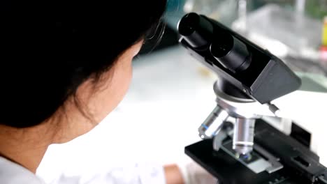 Female-scientist-looking-microscope-eyepiece