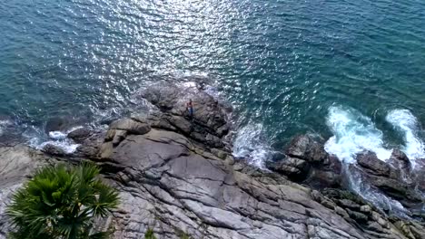 Aerial:-Two-partners-doing-Acro-Yoga-on-the-rocks-near-the-sea.