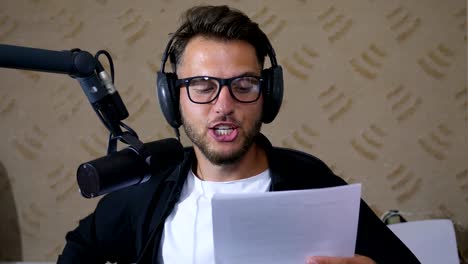 recording-studio,-close-up-young-man-in-glasses-reads-the-text-into-microphone-while-working-on-radio