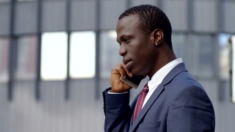 profile-of-young--black-business-man-talking-by-phone-in-the-street