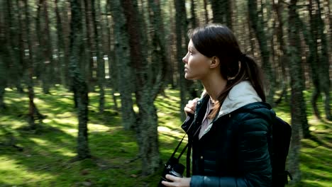 Woman-walking-alone-in-the-forest-with-binoculars