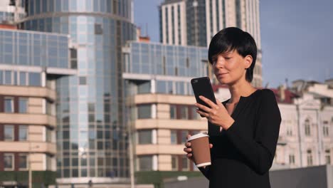 Cheerful-girl-enjoy-coffee-use-smartphone-outdoors.