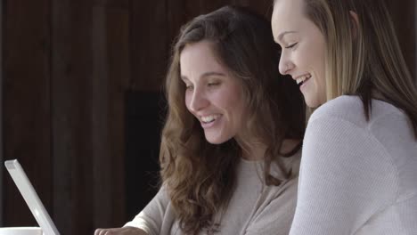 Two-young-women-in-cafe-taking-selfies-together-with-digital-tablet