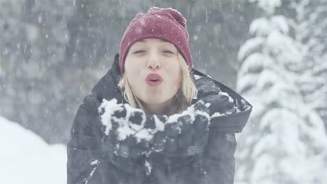 Close-up-shot-of-a-beautiful-young-Asian-woman-blowing-snow-towards-the-camera