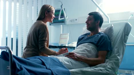 In-the-Hospital,-Man-Recovering-from-Illness-Lying-in-Bed,-Loving-Wife-Visits-Him.-They-Embrace-and-Love-Each-Other-Very-Much,