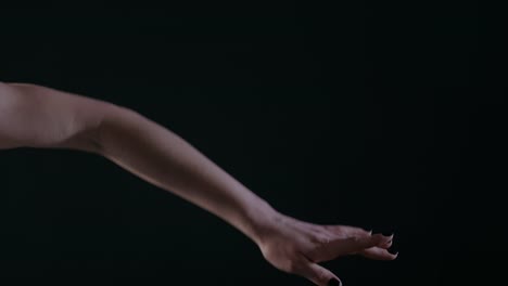 Ballerina-dancing-on-stage-or-dark-classroom-studio,-close-up-of-only-hands-with-magic-light-on-background,-4k