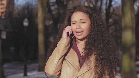 Mittlere-Aufnahme-einer-schönen-jungen-Frau-Gespräch-auf-ihr-Telefon-an-einem-Stadtpark