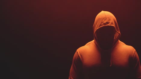 Muscular-black-man-standing-on-a-foggy-dark-red-background,-wearing-a-hoodie