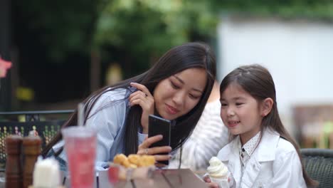 Kleines-Mädchen-posiert-mit-Eis-bei-Smartphone-Kamera
