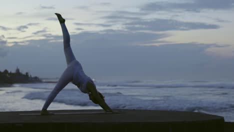 Frau-stehend-Split-Pose-am-Strand-zu-tun