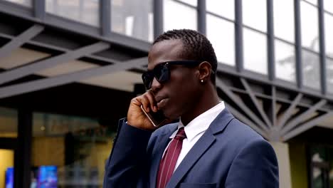 Busy-confident-black-african-manager-talking-by-phone-in-the-street