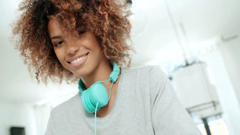 Feliz-afro-americano-joven-con-auriculares-posando-para-una-cámara.