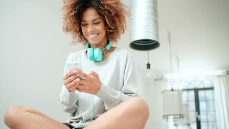 Beautiful-young-afro-american-woman-texting-on-mobile-phone-at-home.