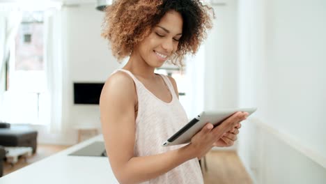 Smiling-happy-Afro-American-woman-using-pc-tablet-at-home.