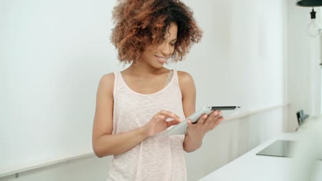 Smiling-happy-Afro-American-woman-using-pc-tablet-at-home.