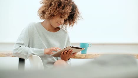 Smiling-happy-Afro-American-woman-using-pc-tablet-at-home.