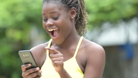 Young-happy-African-woman-using-phone-outdoors