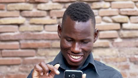 Retrato-de-sonriente-hombre-africano-americano-desplazamiento-su-smartphone.-Tecnología,-comunicación,