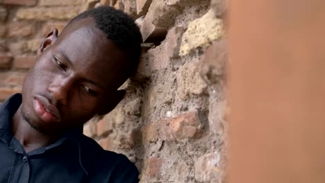 sad-pensive-young-black-african-man-leaning-at-the-wall