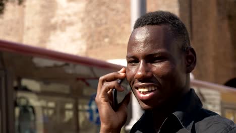 smiling-happy-young-african-man-talking-by-phone--outdoor