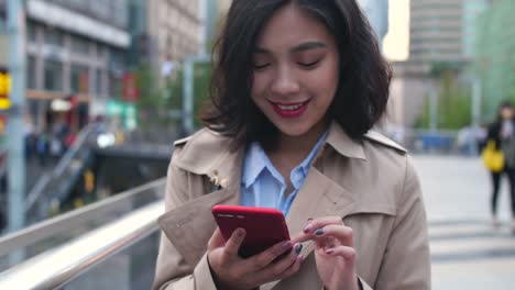 Una-bonita-asiática-joven-uso-teléfono-móvil-en-la-ciudad